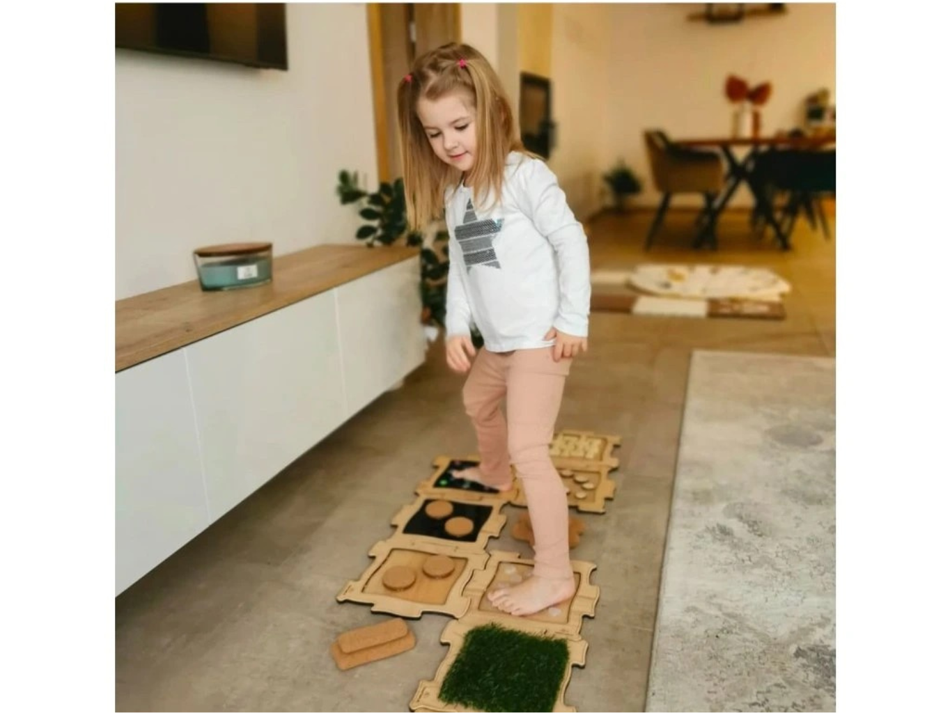 Holčička chodí po senzomotorickém puzzle FunnyTouch – dřevěné plátky a tráva - hmatové podložky pro chůzi naboso